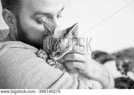 Black And White Photo Of Beard Young  Man Cuddling Cute Devon Rex Kitty. Spending Time With Cat, Boo
