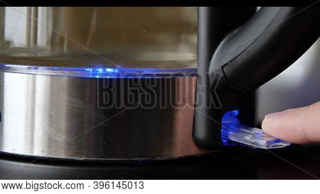 Pressing Button Of Kettle. Media. Close-up Of Man Turning On Electric Kettle With Lighting. Beautifu