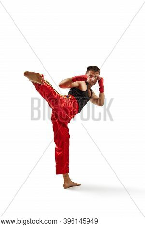 Athletic Man In Red Sports Bandages On His Hands Making Kick During Boxing Exercise, Isolated On Whi