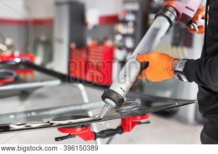 Glazier Applying Rubber Sealing To Windshield In Garage, Close Up. High Quality Photo