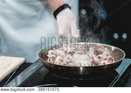 The Chef Cooks The Small Octopus On A Metal Frying Pan