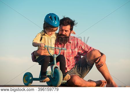 Father Teaching Son Riding Bike. Happy Dad Helping Excited Son To Ride A Bicycle. Trust And Support.