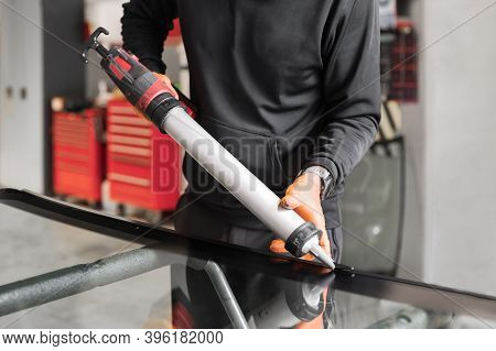 Glazier Applying Rubber Sealing To Windshield In Garage, Close Up. High Quality Photo