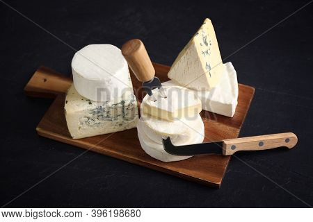 Different Types Of Cheese, Knife And Fork On Black Table