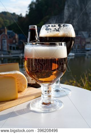 Drinking Of Dark And Strong Belgian Abbey Beer With Cheeses With Nice View On Maas River And Town Di