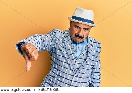Mature middle east man with mustache wearing vintage and elegant fashion style looking unhappy and angry showing rejection and negative with thumbs down gesture. bad expression. 
