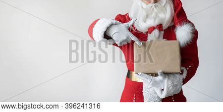 Close-up Of Santa Clauss Hand Holding A Box Wrapped In Craft Paper.