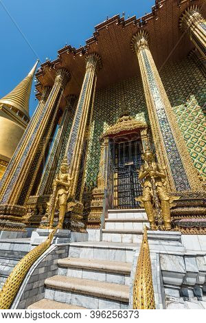 Bangkok, Thailand - December 7, 2019: View Of The Golden Giant Statues Guarding Massive Door To Phra