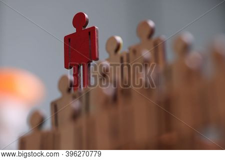 Red Wooden Toy Man Standing Above Others Close-up. Leadership Qualities Concept