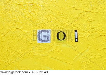 Cut Out Letters And Composed Word Go! On Blurred Yellow Background