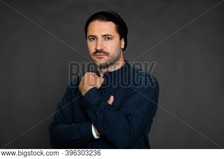 Handsome Mustached Unshaven Guy In Knitted Cap Posing Looking At Camera On Dark Gray Studio Backdrop