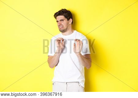 Digusted Guy Refusing And Grimacing, Looking At Something With Aversion, Standing Over Yellow Backgr
