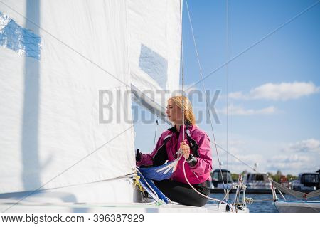 A Young Athlete In A Pink Jacket, Conducts Training On Equipping A Single-masted Sports Yacht On The