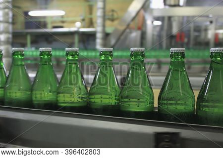 An Automatic Conveyer Belt With Green Glass Bottles For Beverages. Concept Of Producing Clean Bottle