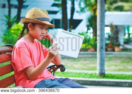 Girls Sit And Watch The Tablets In The Park. She Looks Tired To Watch.