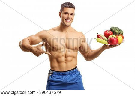Fit musuclar young man posing topless with a plate full of fruits and vegetables isolated on white background