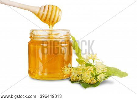 Full Jar With Linden Honey, Lime Flowers And Honey Dripping From Dipper Into Glass Jar Isolated On W