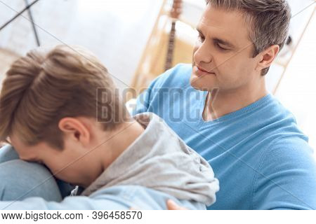 Father Sitting On Couch Near His Son, Tries To Comfort Him, But Problem Teenager Doesn't Want To Lis