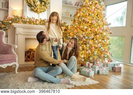 Young Family Feeeling Happy Sitting Near The New Year Tree