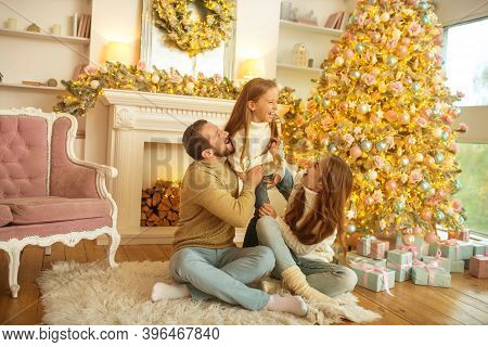 Young Family Feeeling Happy Sitting Near The New Year Tree