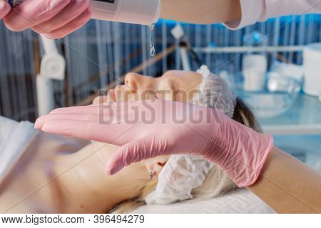 A Professional Beautician Applies Gel To A Gloved Hand.