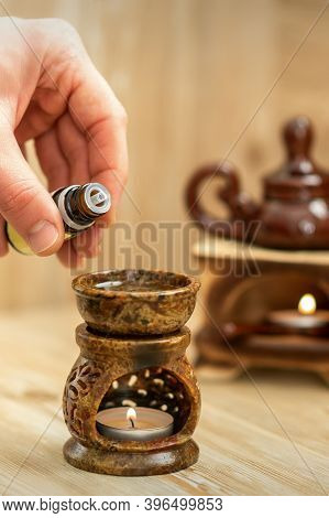 Hand Of Therapist Pours Drops Of Essential Oil To Ceramic Diffuser In Spa Salon