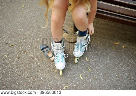 Young Girl Putting On Her Inline Roller Skates On Beautiful Summer Day In A Park. Child Enjoying Rol