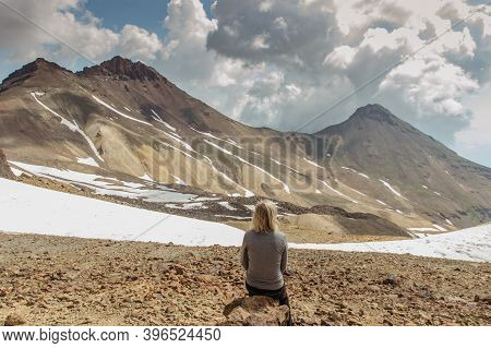 Girl Sitting On The Top Of Aragats Mountain, Armenia Snowy Peaks In Background.backpacker Enjoying V