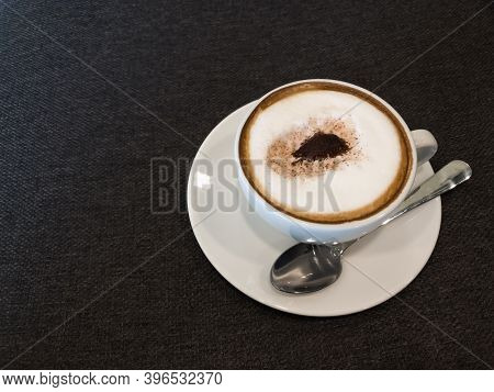 Coffee In White And Stanless Spoon On Black Fabric Background.copy Space.