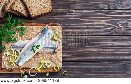 Herring Fillet With Parsley And Onions On A Cutting Board, Top View, Dark Wooden Background. Traditi