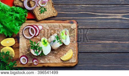 Herring Roll On A Skewer With Parsley, Onion And Lemon Wedge, Top View. The Sandwiches Are Arranged 