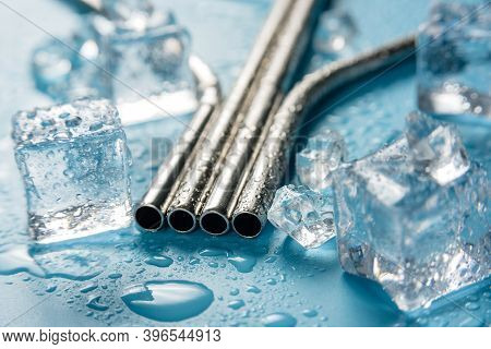 Metal Cocktail Pipes On A Blue Background Among Melting Ice Ubiks. Photo Of A Steel Cocktail Tube Cl