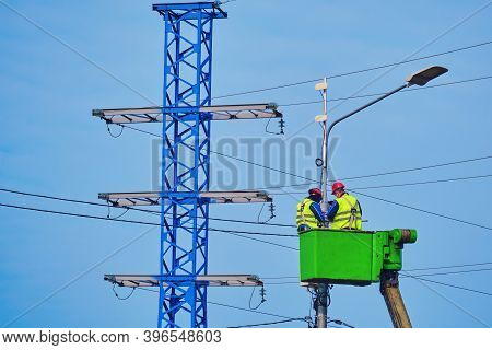 Male Electricians Repair A Power Tower Standing At A High Altitude