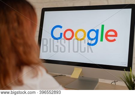A Woman Sits At A Computer With A Google Logo On The Monitor