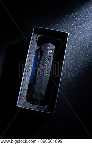A Folding Knife In A Cardboard Box. Packaged Knife. Top.