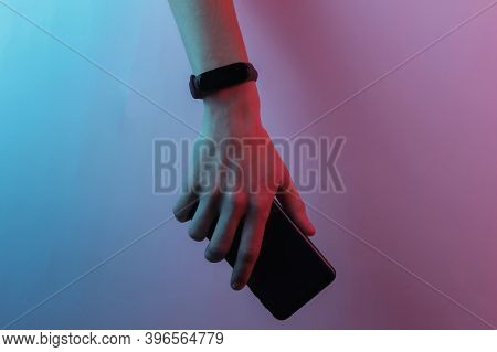 Female Hand With Smart Bracelet And Smartphone. Modern Gadgets. Creative Pop Art Pink Blue Neon Colo