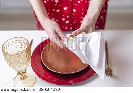 Female Hands Close Up Set The Table For Christmas, Decorating It With White Napkin, Plates And Wineg
