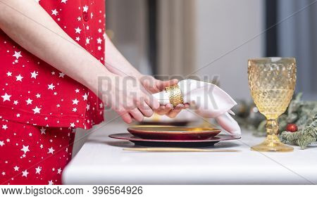 Female Hands Close Up Set The Table For Christmas, Decorating It With White Napkin, Plates And Wineg
