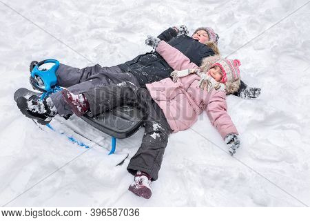 A Happy Boy And Girl Lying Together In The Snow, Making Snow Angels.
