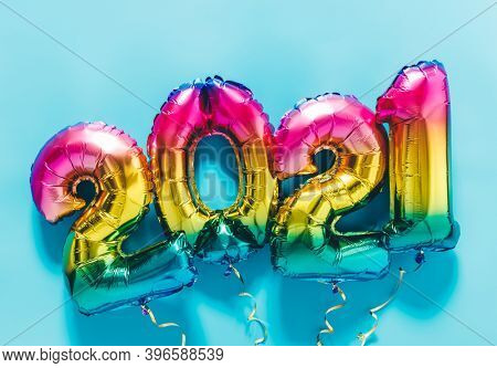 Rainbow colored Foil balloons in the form of numbers 2021 on blue background