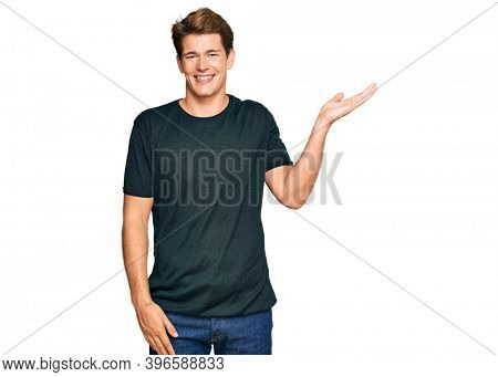 Handsome caucasian man wearing casual clothes smiling cheerful presenting and pointing with palm of hand looking at the camera. 
