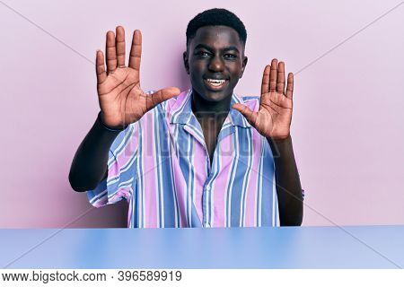 Young african american man wearing casual clothes sitting on the table afraid and terrified with fear expression stop gesture with hands, shouting in shock. panic concept. 