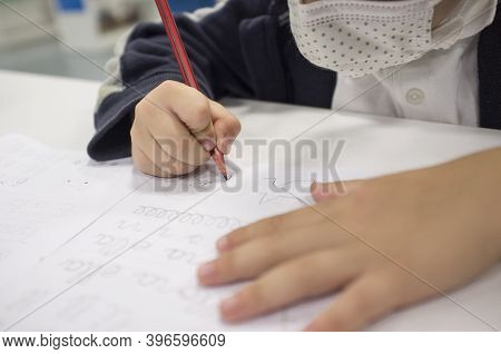 Pre-writter Child Boy Doing Calligraphy Exercises With Booklets. Selective Focus