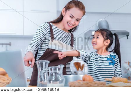 Mother And Duagther Is Learning To Bake And Book From Online Tutorial On Computer Laptop At Home.