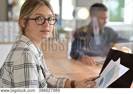 Office worker with eyeglasses working in open space area protected with plexiglas