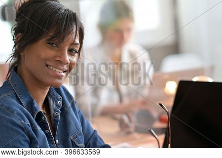 Office worker woman in open space area, protected by plexiglas
