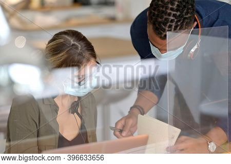 Start-up people working in co-working space office, protected with plexiglas