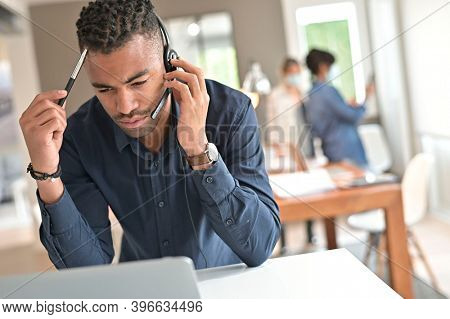 Salesman in co-working office with headsst working on laptop in open space office