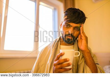 Arabian Indian Man Drinking Hot Lemon Dinder Masala Tea In Morning Bedroom While Feeling Cold Covere