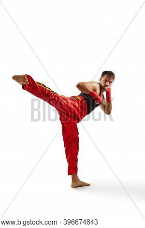 Athletic Man In Red Sports Bandages On His Hands Making Kick During Boxing Exercise, Isolated On Whi